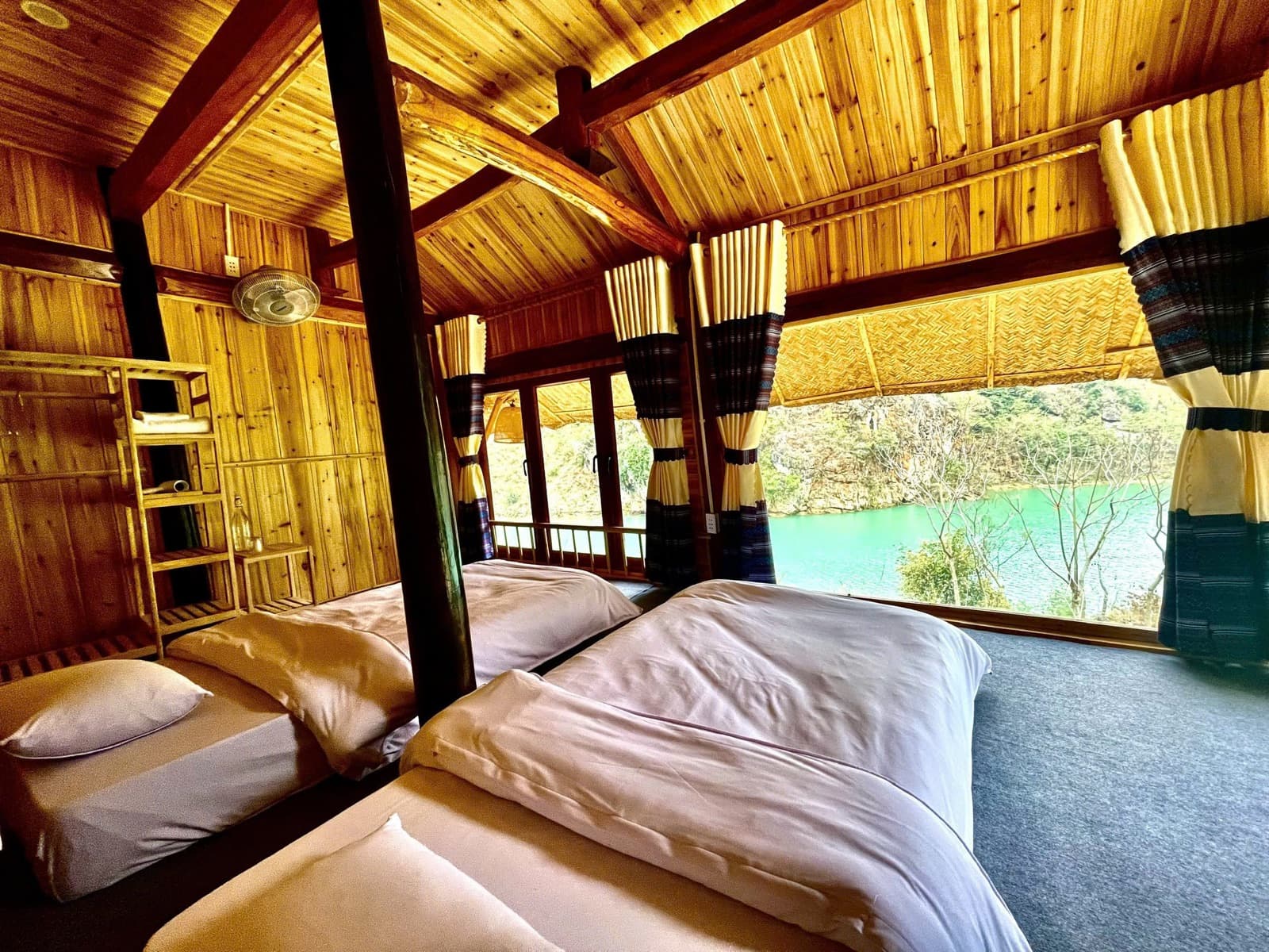 A wooden homestay room with big windows onto the river