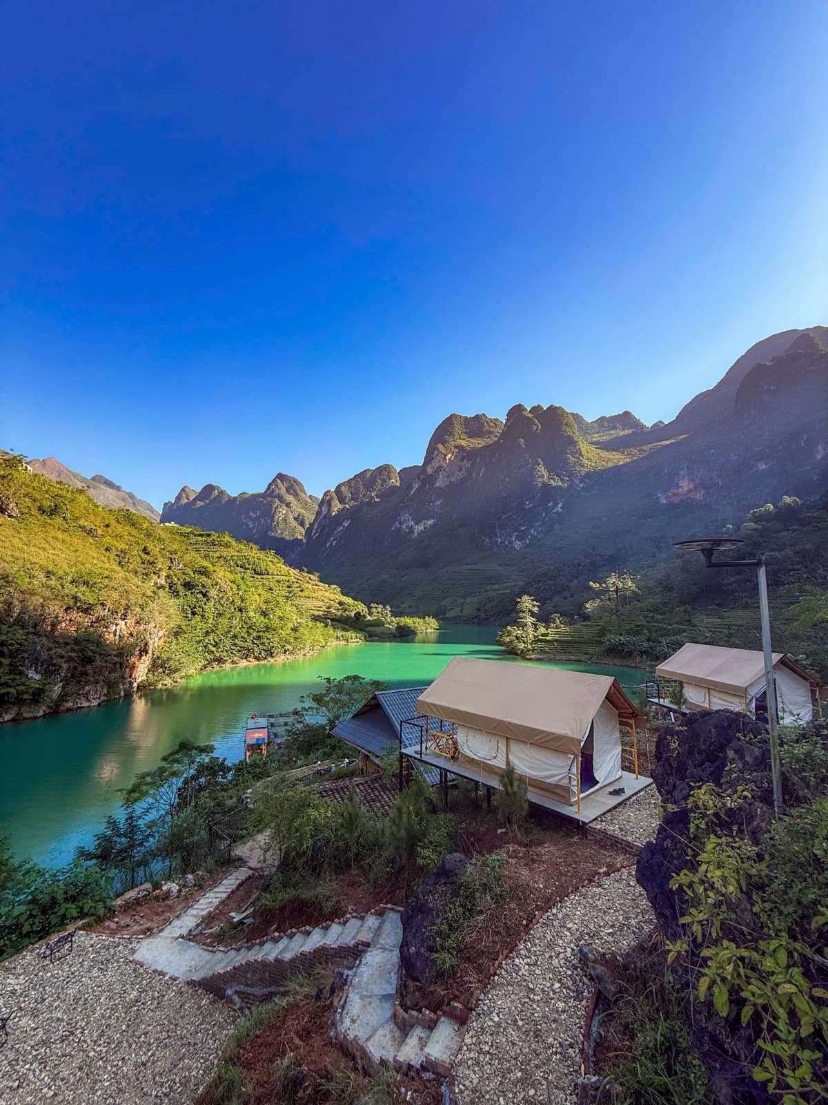 Glamping tents above a turquoise lake and limestone peaks